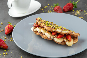 sandwich waffles with banana, strawberry and chocolate and pistachio on top