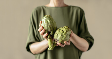 Woman holding fresh ripe artichokes in her hands