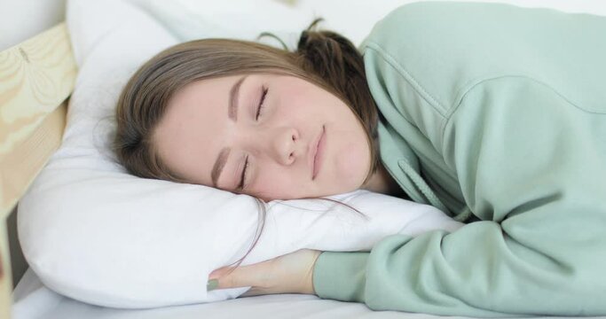 Young beautiful woman is falling with her head on the pillow tired and falling asleep. Close-up.