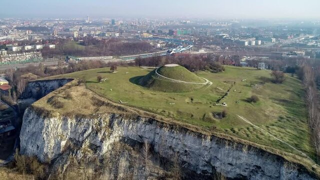 Krakus Mound in Krakow, Poland. The origin of the mound, probably early medieval kurgan, is not known. Old quarry in front. City panorama in the background. Aerial 4K video