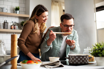 Happy smiling couple cooking together. HUsband and wife preparing fresh meal at home.