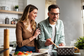 Happy smiling couple cooking together. HUsband and wife preparing fresh meal at home.