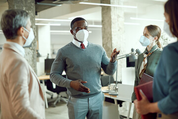 African American corporate manager talking while holding team meeting in the office during coronavirus pandemic.