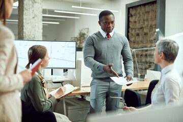 African American CEO discussing about business reports with his team on a meeting in the office.