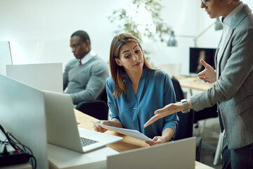 Obraz premium Female entrepreneur going through reports with her business mentor while working in the office.