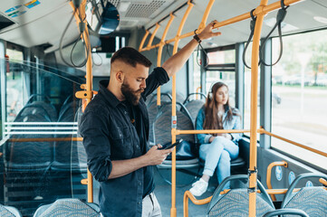 Man standing in a moving bus while using a smartphone