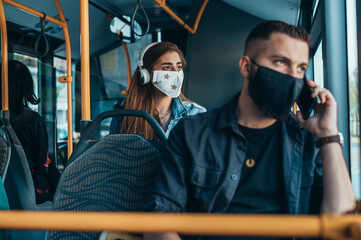 Woman wearing protective mask and using a headphones while riding a bus