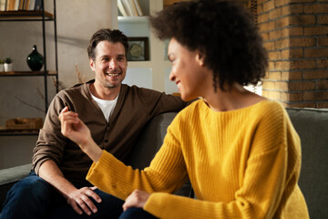 Young couple sitting and talking at home. Woman and man flirting and laughing.