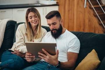 Couple using a digital tablet while relaxing at home