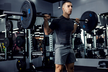 Determined to win. A motivated fitness man with a barbell on his shoulders and a stable body...
