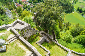 Fototapeta premium Scenic view from the top of the castle ruins of Hohengundelfingen, Germany down to a fresh green river valley. The ruins show stone walls with stairs, surrounded by deciduous trees and rough rocks.