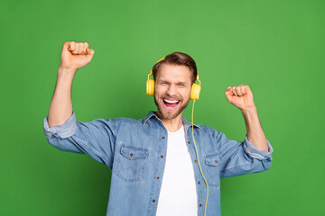 Photo portrait of young guy listening music wearing headphones dancing relaxing at party isolated vibrant green color background