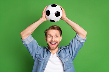 Photo portrait of football fan keeping soccer ball smiling amazed isolated bright green color...