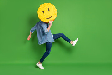 Full length body size side profile photo of man hiding face behind yellow smile isolated vivid green color background - obrazy, fototapety, plakaty