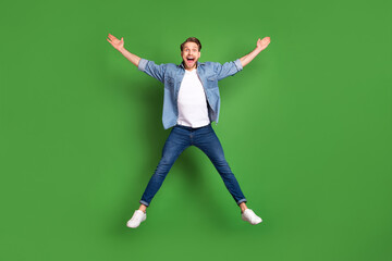 Full length body size photo of young guy jumping up careless playful isolated bright green color...