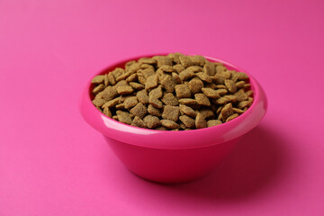 Pet bowl with feed on pink background
