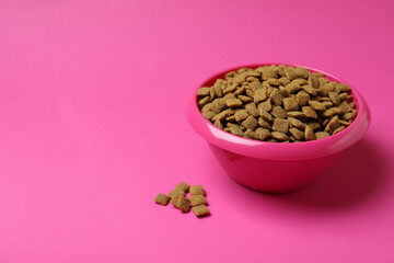 Pet bowl with feed on pink background