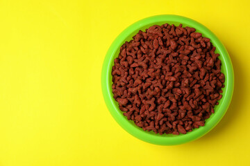 Pet bowl with feed on yellow background