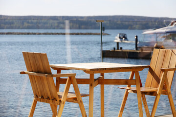 Empty wooden table with chairs on the veranda of a summer cafe on the city embankment. Sunny warm day by the lake