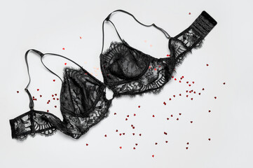 Lace sexy black womens underwear, red heart confetti on gray background flat lay top view copy...