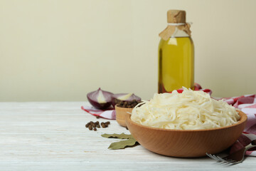 Fresh sauerkraut and ingredients on white wooden table
