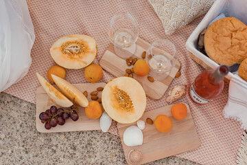 Picnik with rose wine, grapes and melon on the pink blanket
