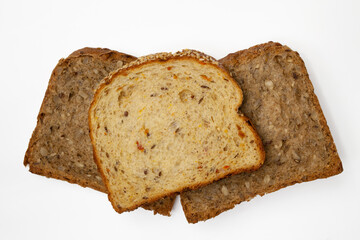 Three slices of wholegrain bread with vegetables and seeds of sunflower, flax, and sesame. Healthy vegetarian food. Isolated flatlay.