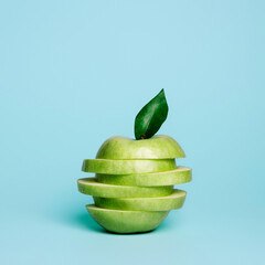 Green apple slices stacked vertically on the vibrant blue background. Creative fruit concept....