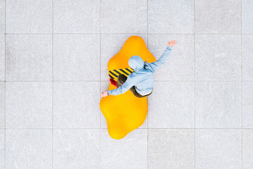 Aerial view of professional skateboarder jumping over the modern yellow object in urban skate park in Kaunas, Lithuania.