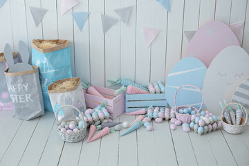 Baskets with lot colorful Easter eggs and carrots! Spring home decoration and easter decor. Holiday flags on wooden white wall. Children's room in the Easter style. Colorful Easter room interior.	
