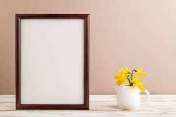 Wooden frame with spring snowdrop flowers narcissus on beige pastel background. top view, copy space, mockup, template.