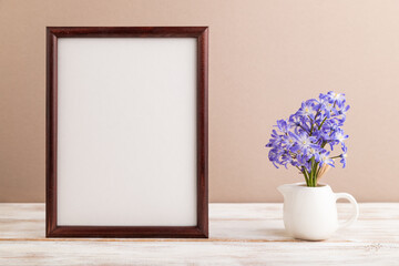 Wooden frame with spring snowdrop flowers chionodox on beige pastel background. top view, copy space, mockup, template.
