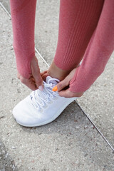 Fototapeta na wymiar Attractive woman in sportswear tying sport shoes snickers. Concept of fashionable sport outfit, vertical photo. The concept of sports, healthy lifestyle, fitness exercise, stretching