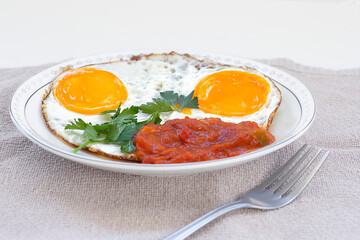 Side view of fried eggs with parsley and seasoning of vegetables on a plate closeup. Selective focus