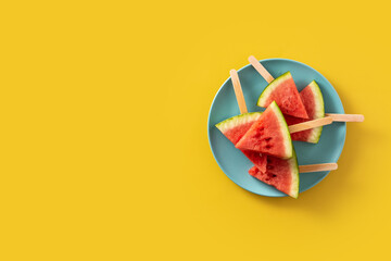 Watermelon slices popsicles and ice on yellow background. Copy space	