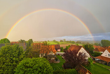 A wonderful summer rainbow landscape. Houses and field in the countryside. 
The green landscape...