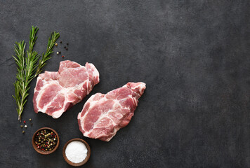 Fresh meat. Raw pork steak with spices on a black background. View from above.