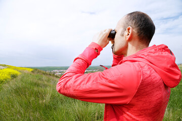 Man hiking and birdwatching looking through binoculars