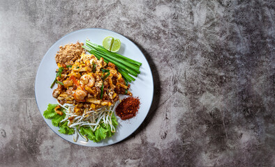 SHRIMP PAD THAI with copy space on a dark tone background,  Pad thai, or phad thai is a stir-fried rice noodle dish commonly served as a street food and at most restaurants in Thailand
