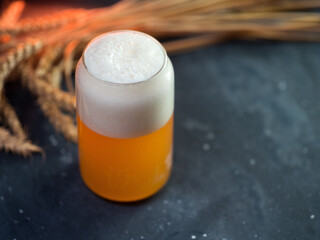 Creative glass of wheat beer on a black table, wheat ears and copy space . Craft Beer concept