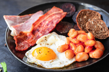 english breakfast fried egg black pudding blood sausage, cereal bread, beans, bacon, scrambled eggs, wholesome food healthy meal snack copy space food background rustic top view