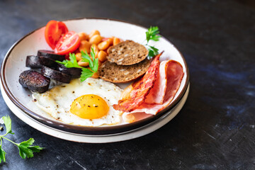 english breakfast fried egg black pudding blood sausage, cereal bread, beans, bacon, scrambled eggs, wholesome food healthy meal snack copy space food background rustic top view