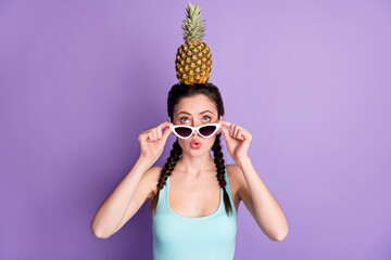 Portrait of attractive comic funny amazed girl holding on head ananas pout lips isolated over violet purple color background