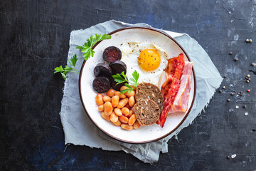 english breakfast fried egg black pudding blood sausage, cereal bread, beans, bacon, scrambled eggs, wholesome food healthy meal snack copy space food background rustic top view