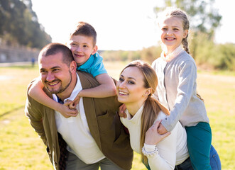 happy family of parents with two children enjoy a walk in city park