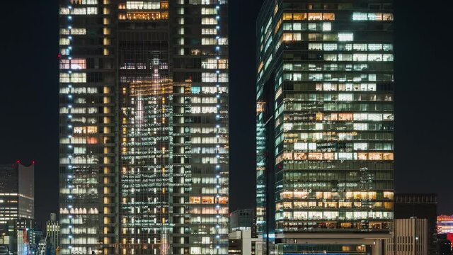 Time lapse of office building with elevator moving, people working, window facade view at night. Corporate business, office worker life, or building exterior architecture concept