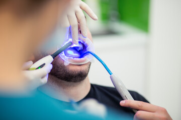 Dentist doing the teeth whitening to the patient