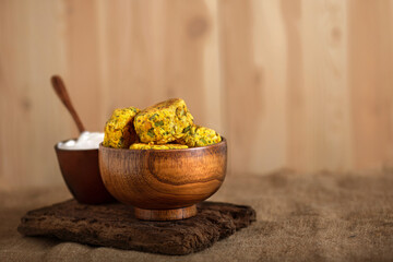 Homemade baked veggie chickpea burgers with white yogurt sauce in brown wooden bowl on burlap cloth. Tasty lentils cutlets with greens and spice. Rustic style. Copy space