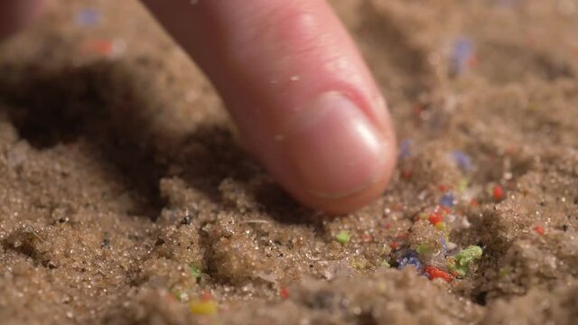 hands showing microplastics on the beach. small plastic pieces harmful to ocean and aquatic life. marine plastic debris.