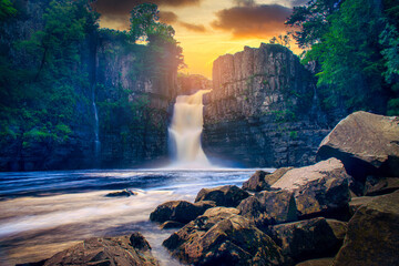 High Force Waterfall views from the south bank of the River Tees on the Pennine Way at sunset in woodland, UK.
